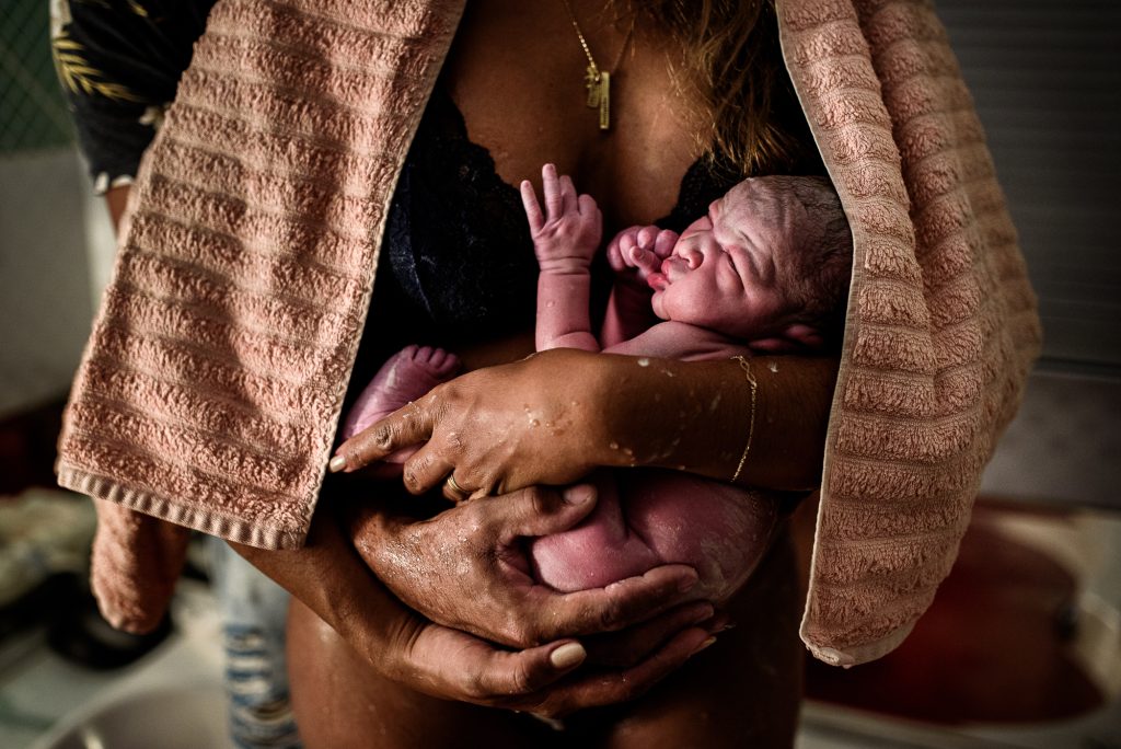 mulher carregando bebê recém nascido em parto domiciliar, foto de monique olive