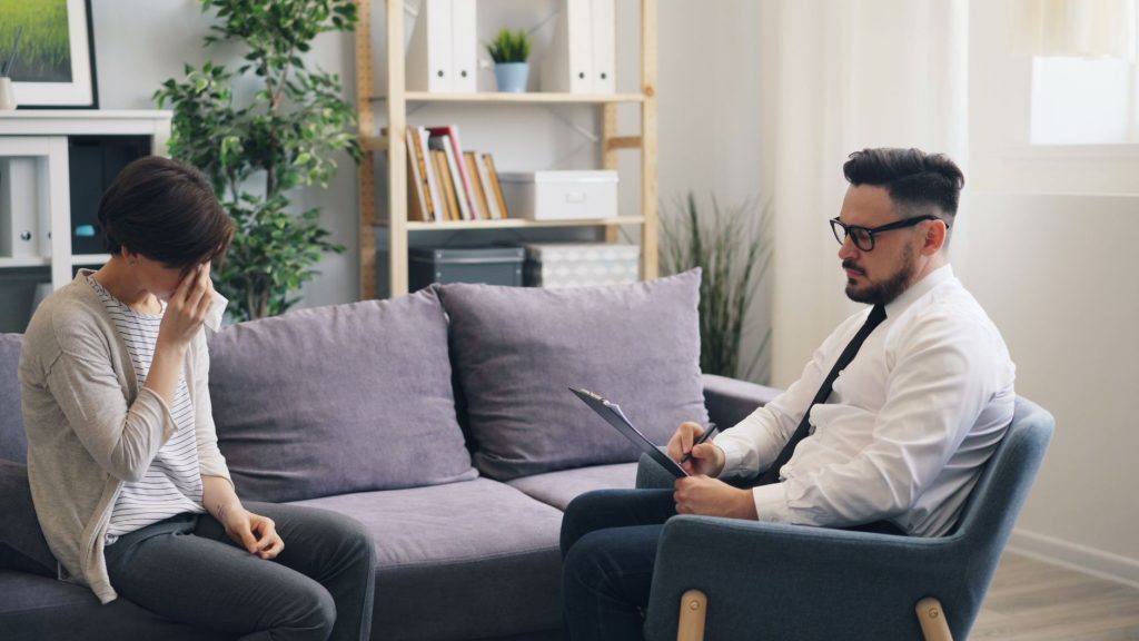 A therapy session showing a woman consulting a professional therapist in a cozy office environment.