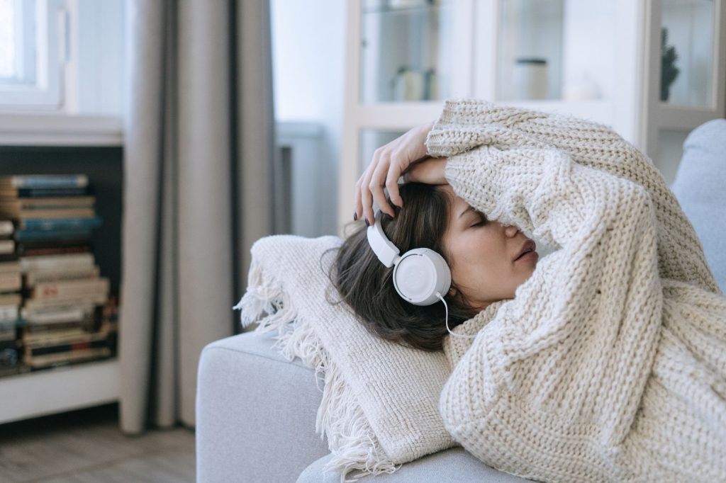 A young woman in a knitted sweater relaxing with headphones, conveying a sense of calm and introspection.
